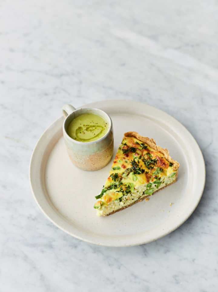 Plate with a slice of asparagus quiche and a mug of asparagus soup