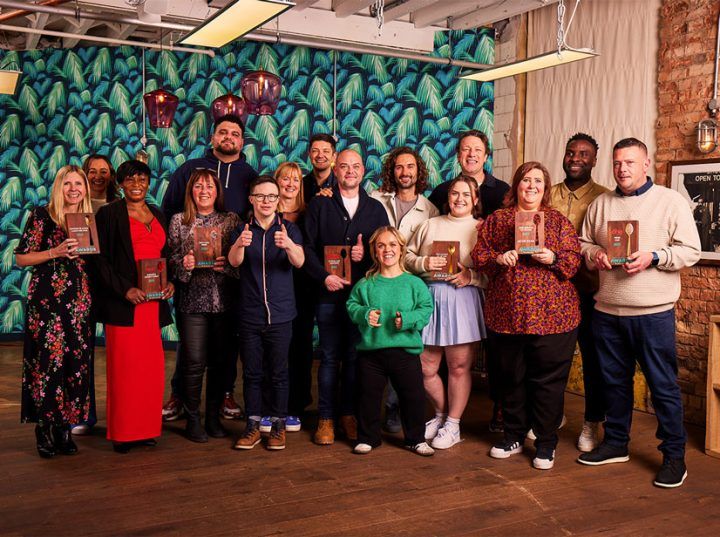 All the winners from the Good School Food Awards 2023, plus judges, holding their award and smiling at the camera