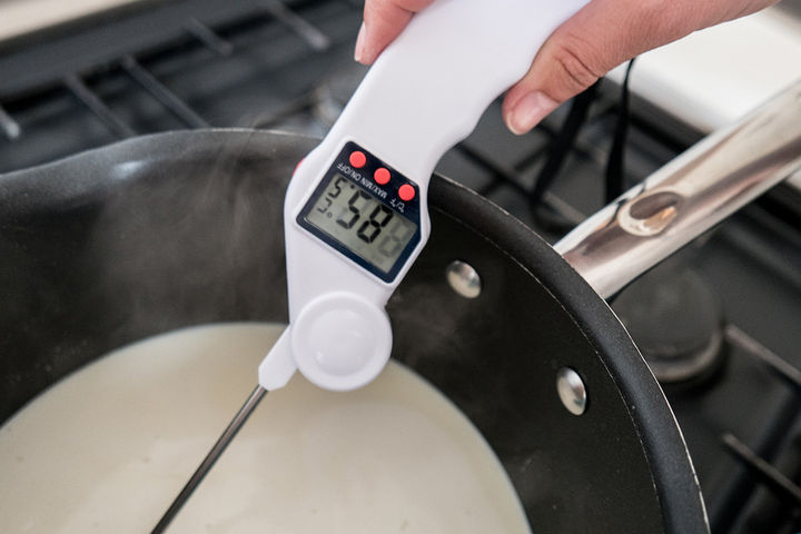 Image of thermometer being used to check the temperature of the milk and cream being heated
