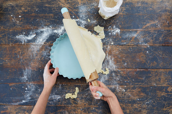 Image of pastry base being laid into a pastry tin 