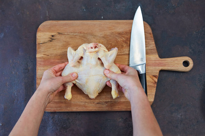 Image of splayed open, whole raw chicken, breast-side down.