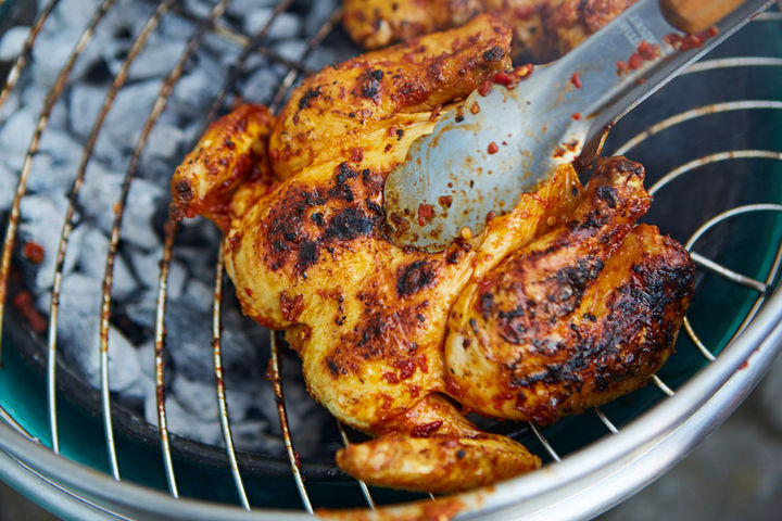 Image of marinaded spatchcock chicken being cooked on the BBQ