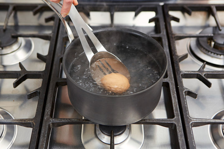 Image of egg being lowered into boiling water