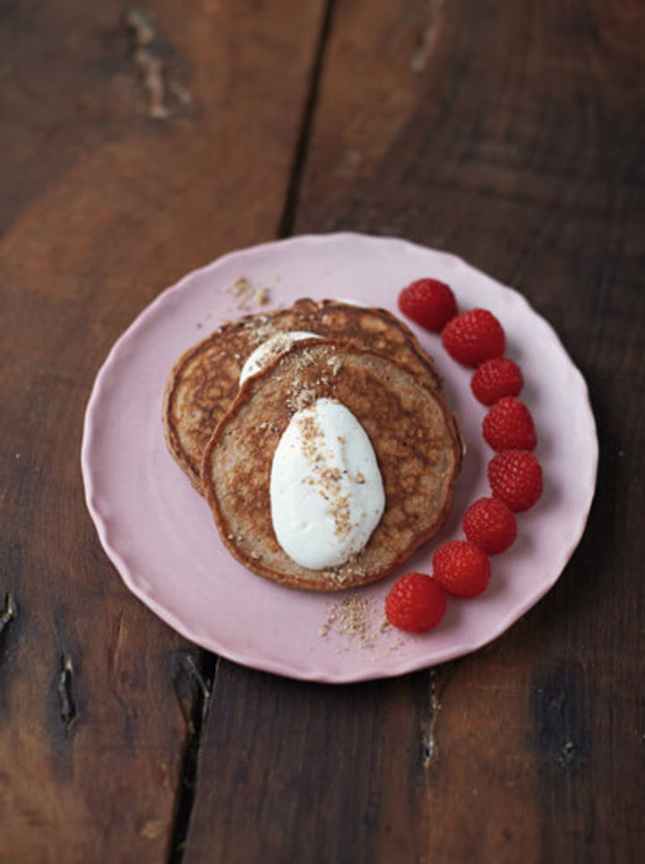 stack of pancakes with raspberries and granola dust