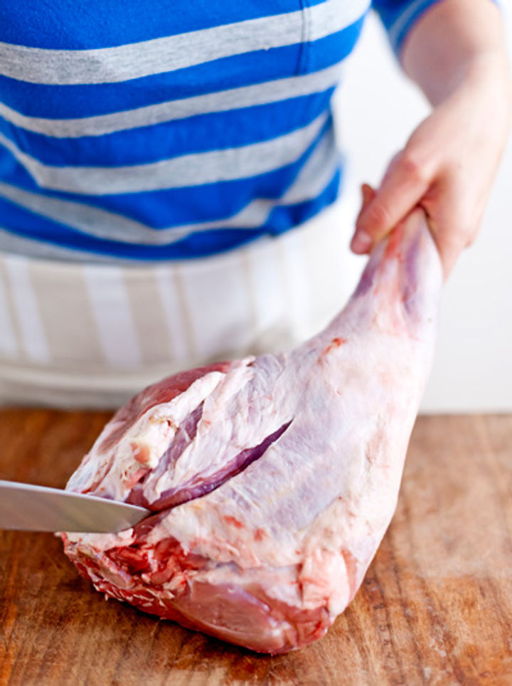 Image of carefully cutting down the lamb leg to expose the bone